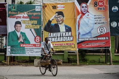 Warga mengayuh sepedanya saat di depan alat peraga kampanye (APK) di Makassar, Sulawesi Selatan, 28 November 2023. ANTARA/Arnas Padda