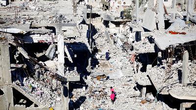 Anak-anak Palestina berjalan di antara rumah-rumah yang hancur akibat serangan Israel di selatan Jalur Gaza, 29 November 2023/REUTERS/Mohammed Salem