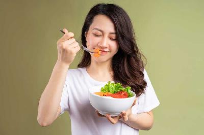 Ilustrasi seorang wanita memakan sayur. Shutterstock