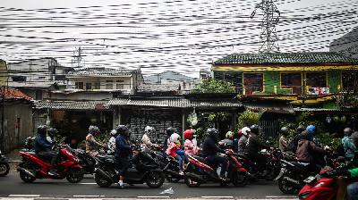 Pengendara melintas di bawah instalasi jaringan kabel utilitas yang semrawut di kawasan Kramat Jati, Jakarta, 6 Januari 2024/Tempo/Hilman Fathurrahman W