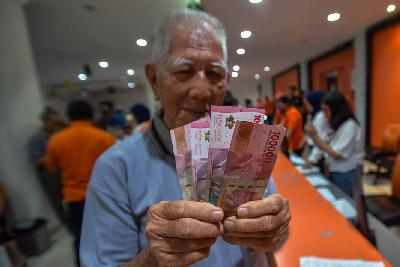 Warga menunjukkan uang yang diterima saat penyerahan Bantuaan Langsung Tunai (BLT) El Nino di Kantor Pos Oceania Jakarta Barat, 29 Desember 2023. Tempo/Tony Hartawan
