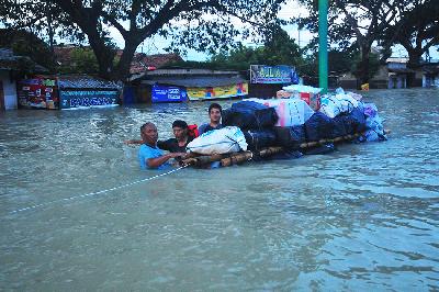 Warga korban banjir mengangkut sembako menggunakan rakit melintasi jalan Pantura yang terendam banjir di Karanganyar, Demak, Jawa Tengah, 12 Februari 2024. ANTARA/Yusuf Nugroho