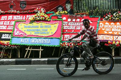 Pengendara sepeda melintas di dekat karangan bunga berisi dukungan hak angket di depan Kantor DPP PDI Perjuangan di Jakarta, 8 Maret 2024. ANTARA/Asprilla Dwi Adha