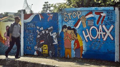 Warga melintas di depan mural menolak berita hoax di Margonda Depok, Jawa Barat, Juli 2023. Tempo/M Taufan Rengganis