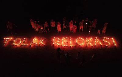 Warga yang terdampak proyek Rempang Eco-City beraktivitas di dekat tulisan "tolak relokasi" dari lampu pelita di Sembulang, Pulau Rempang, Batam, 7 April 2024. Foto: Istimewa
