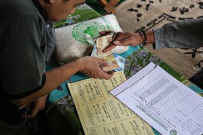 Petugas panitia amil zakat menerima uang tunai dari warga pembayar zakat fitrah di Semarang, Jawa Tengah, 9 April 2024. ANTARA/Makna Zaezar