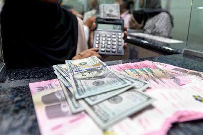 Karyawan menunjukkan uang pecahan 100 dolar Amerika di penukaran mata uang asing di Jakarta, 16 April 2024. TEMPO/Tony Hartawan