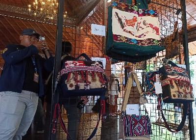Seorang pengunjung mengambil foto beberapa tas yang dipamerkan dalam Festival Tas Nusantara (Festara) 2024 yang digelar di Balai Kota Solo, Jawa Tengah, Sabtu-Minggu, 22-23 Juni 2024. TEMPO/SEPTHIA RYANTHIE