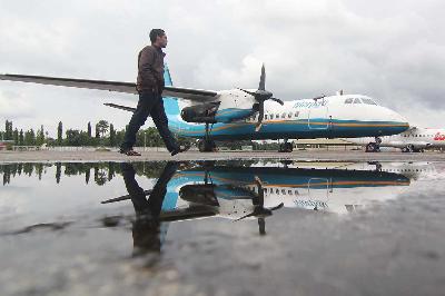Seseorang melintas di dekat pesawat MA-60 milik Merpati Nusantara yang di parkir di apron lama Bandara Hasanuddin di Kabupaten Maros, Sulawesi Selatan, 2014. Dok.TEMPO/Fahmi Ali