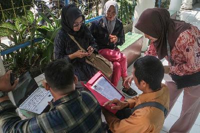 Petugas membantu orang tua calon siswa mendaftar penerimaan peserta didik baru (PPDB) secara daring di SMP Negeri 2 Cibinong, Kabupaten Bogor, Jawa Barat, 1 Juli 2024. ANTARA/Yulius Satria Wijaya