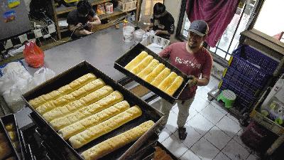 Pekerja mengangkat loyang berisi roti manis yang baru matang di sentra pabrik roti rumahan Babakan Rahayu, Kelurahan Kopo, Bandung, Jawa Barat, 17 Juli 2024. Tempo/Prima Mulia