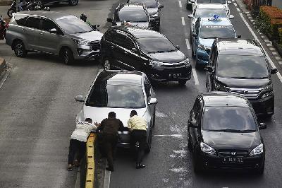 Petugas keamanan gedung mencoba membantu mengevakuasi mobil yang mengalami kecelakaan di jalan HR. Rasuna Said, Jakarta, 17 Mei 2024. TEMPO/ Imam Sukamto