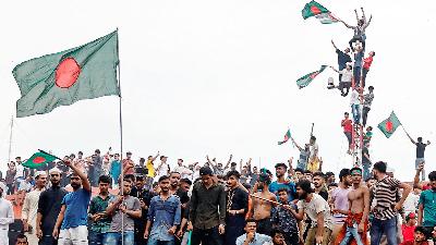 Demonstran mengibarkan bendera Bangladesh dekat kediaman Perdana Menteri, ketika merayakan pengunduran diri PM Sheikh Hasina, di Dhaka, Bangladesh, 5 Agustus 2024. Reuters/Mohammad Ponir Hossain