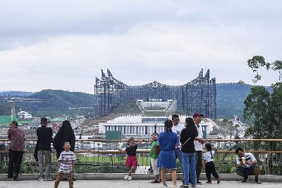 Warga dengan latar belakang Istana Negara IKN di Taman Kusuma Bangsa, Ibu Kota Nusantara, Penajam Paser Utara, Kalimantan Timur, 18 Agustus 2024. ANTARA/Muhammad Adimaja