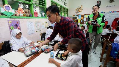 Wakil Presiden terpilih Gibran Rakabuming Raka (tengah) membagikan paket makanan saat meninjau uji coba pelaksanaan program makan bergizi gratis di SD Negeri Klampis Ngasem 3, Surabaya, Jawa Timur, Kamis (1/8/2024).