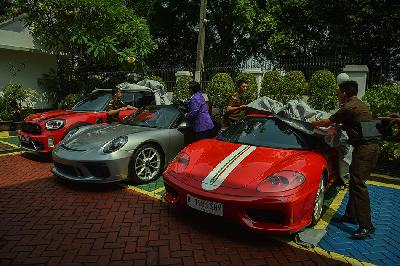 Petugas kejagung membuka kain penutup barang bukti berupa mobil  mewah saat pelimpahan tahap dua kasus dugaan korupsi Timah di Kejaksaan Negeri Jakarta Selatan, Jakarta, 22 Juli 2024. TEMPO/M Taufan Rengganis