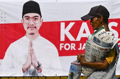 Penjual koran melintas di depan alat peraga sosialisasi bergambar Kaesang Pangarep di Pancoran, Jakarta, 12 Agustus 2024. ANTARA/Muhammad Ramdan