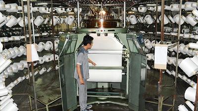 A worker operates a fiber spinning machine at the Asia Pacific Fibers Tbk. factory in Karawang, West Java. asiapacificfibers.com