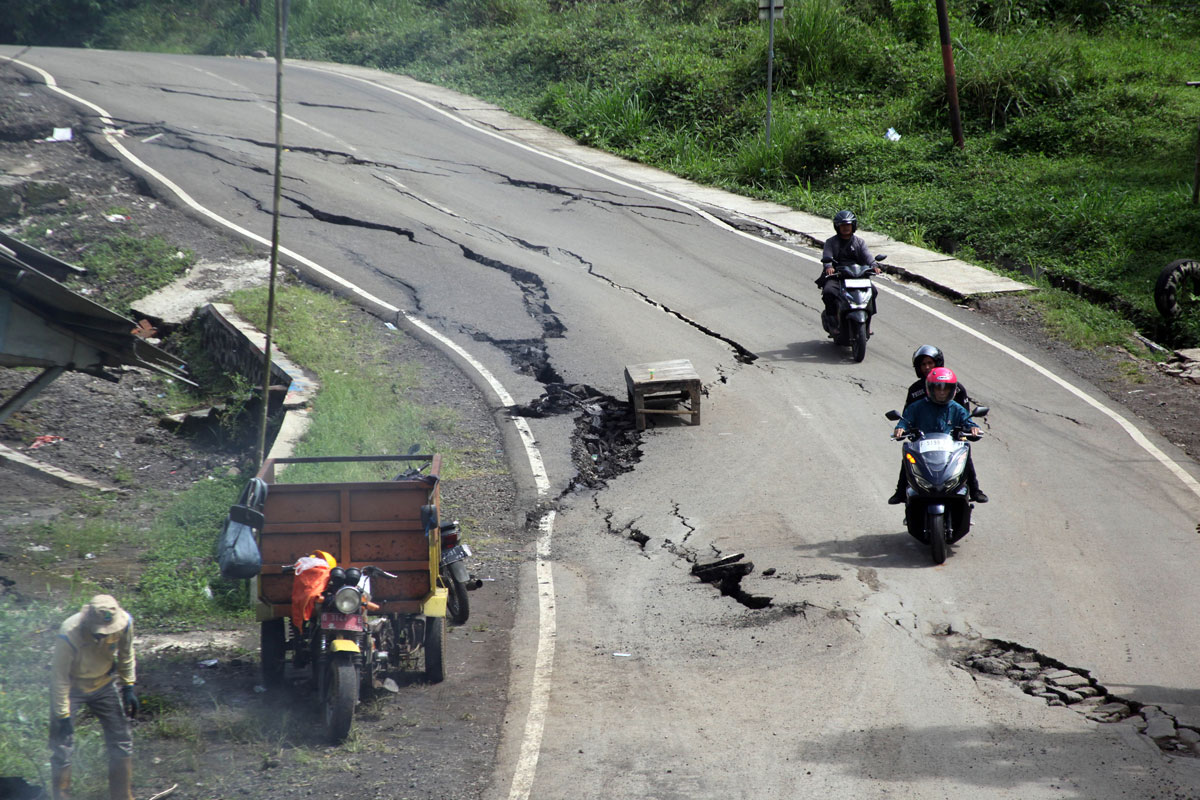 Pengendara motor melewati jalan retak dan amblas di Jalan Raya Baros - Sigaranten, Kabupaten  Sukabumi, Jawa Barat, 8 Desember 2024. . Pergerakan tanah akibat hujan  terus menerus tersebut menyebabkan jalan retak dan amblas sehingga berpotensi menyebabkan kecelakaan. Antara/Yulius Satria Wijaya