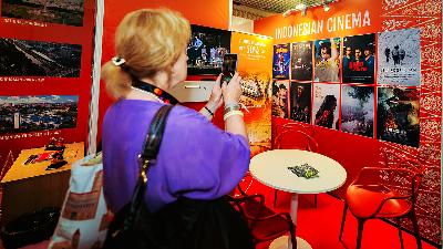 Seorang pengunjung sedang memfoto poster film Indonesia yang dibawa ke Festival Film Internasional Cannes 2025 di Paviliun Indonesia, Cannes, Prancis. Festival ini berlangsung pada 13-24 Mei 2025. Arman Febryan untuk Tempo