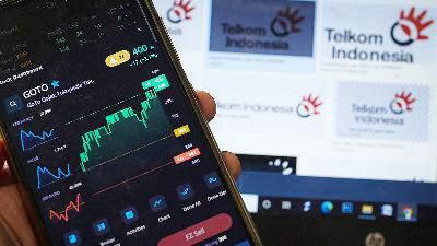 An investor monitors GoTo's stock movement via a cellular phone with the Telkom Indonesia logo in the background, in Jakarta. Doc. Tempo/Hilman Fathurrahman W
