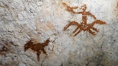 A 67,800-year-old hand stencil (superimposed over a bird figure) in the Liang Metanduno karst cave, Muna, Southeast Sulawesi. Doc. Maxime Aubert
